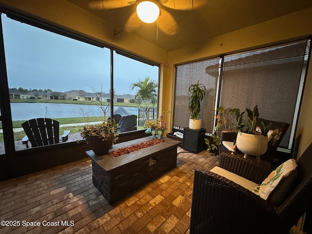 sunroom with a water view and ceiling fan