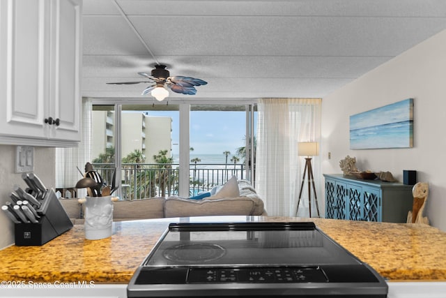 kitchen featuring ceiling fan, range, and white cabinets