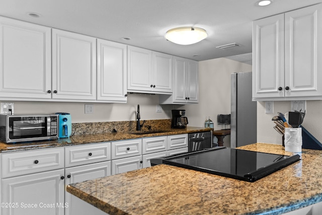 kitchen with appliances with stainless steel finishes, sink, white cabinets, and dark stone counters