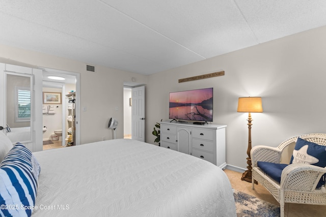 bedroom with ensuite bathroom and a textured ceiling