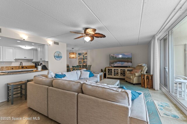 living room featuring light tile patterned flooring, ceiling fan, and a textured ceiling