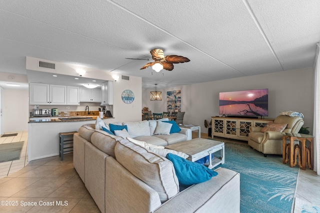 tiled living room with sink, a textured ceiling, and ceiling fan