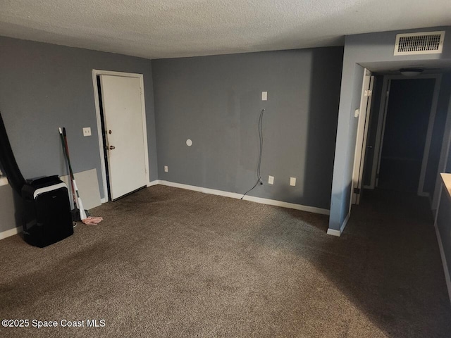 unfurnished room with a textured ceiling and dark colored carpet