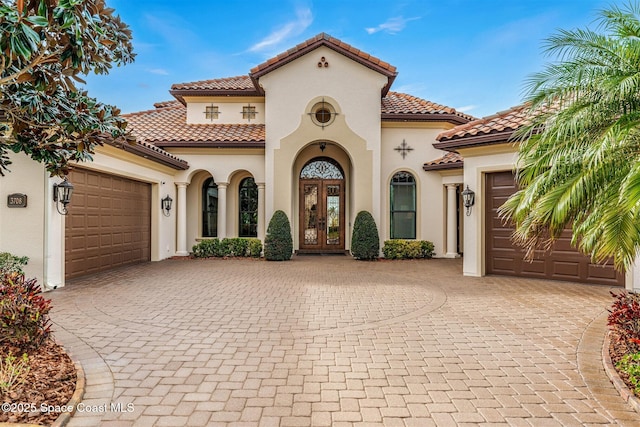 mediterranean / spanish house with a garage and french doors