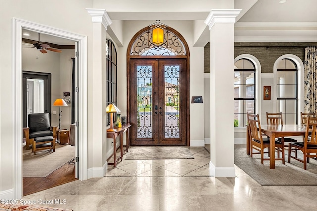 foyer featuring decorative columns and french doors