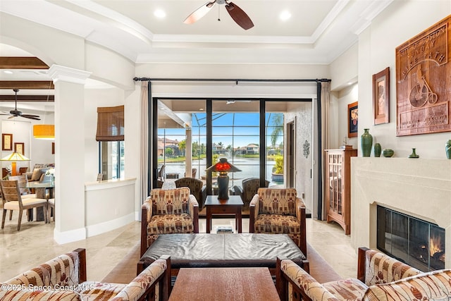 living area featuring a raised ceiling, crown molding, a water view, and ceiling fan