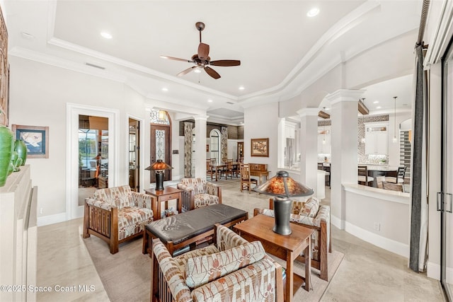 living room with crown molding, a raised ceiling, ceiling fan, and ornate columns