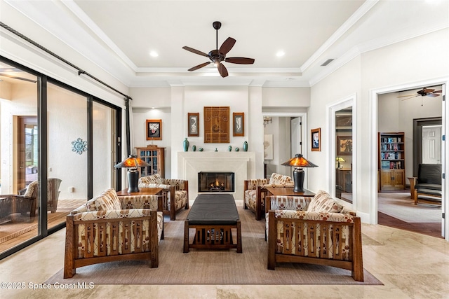 living room featuring crown molding, a raised ceiling, and ceiling fan