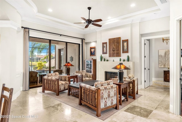 living room with ceiling fan, ornamental molding, a raised ceiling, and a towering ceiling