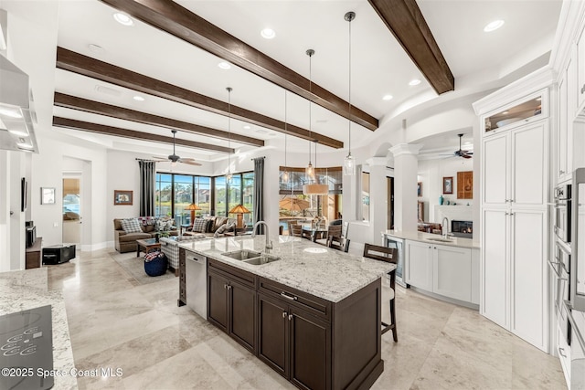 kitchen with a center island with sink, white cabinetry, a breakfast bar, and sink