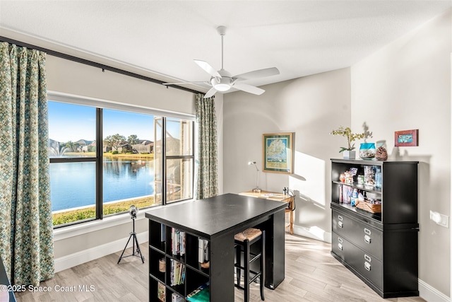 dining room featuring a water view, ceiling fan, plenty of natural light, and light hardwood / wood-style floors