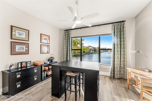 office featuring a water view, ceiling fan, and light hardwood / wood-style flooring