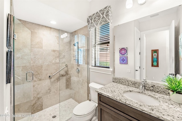 bathroom featuring vanity, toilet, and a shower with shower door