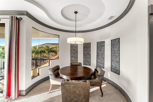 carpeted dining room with a tray ceiling