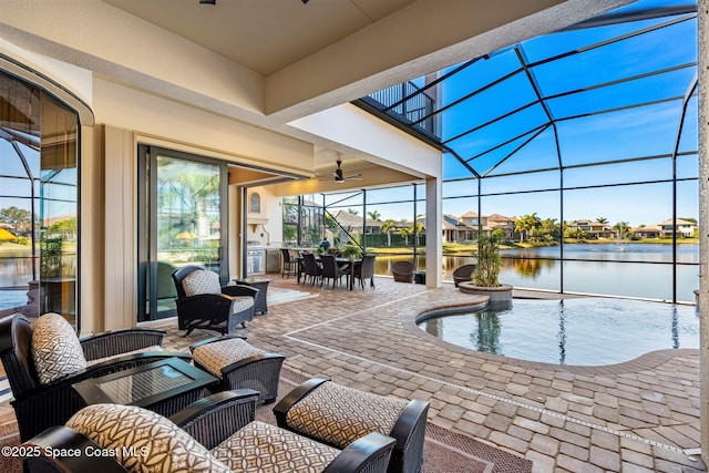 view of swimming pool with a water view, glass enclosure, exterior kitchen, and a patio area