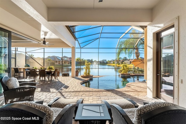 view of patio with ceiling fan, a water view, outdoor lounge area, and glass enclosure