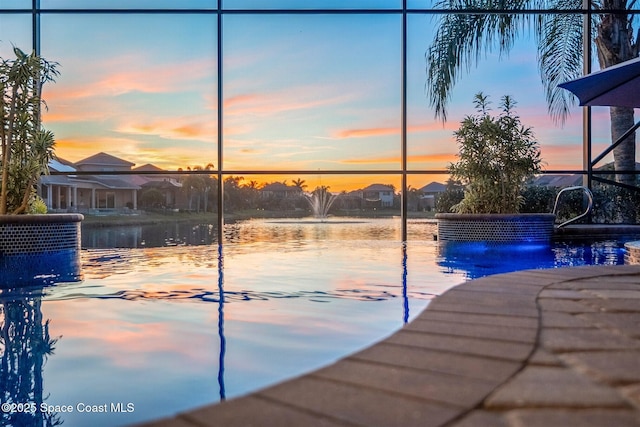 pool at dusk featuring a water view