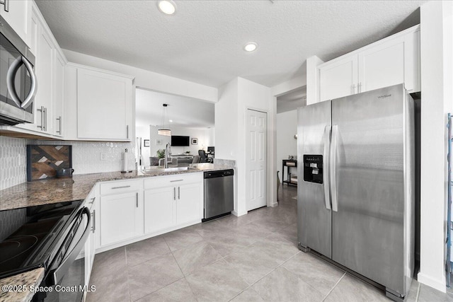 kitchen featuring white cabinetry, stone countertops, hanging light fixtures, stainless steel appliances, and backsplash