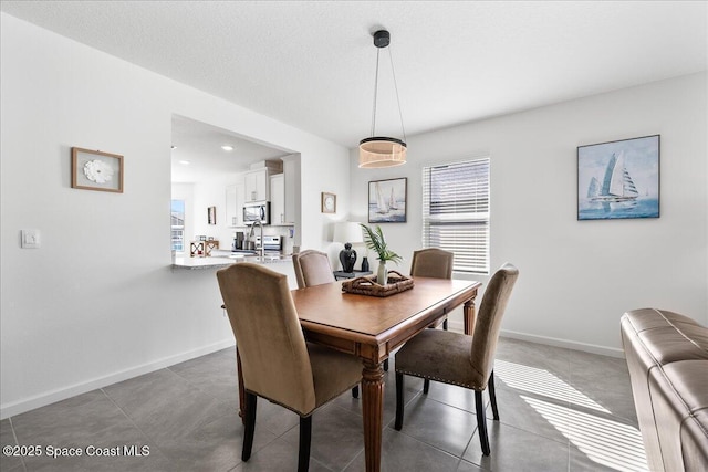 dining space featuring a textured ceiling, dark tile patterned floors, and a healthy amount of sunlight