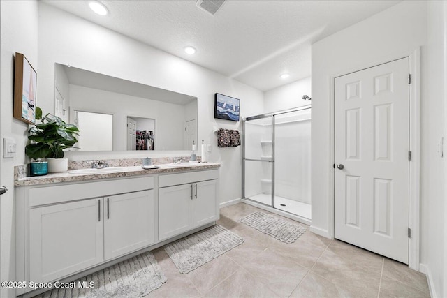 bathroom featuring vanity, an enclosed shower, tile patterned flooring, and a textured ceiling