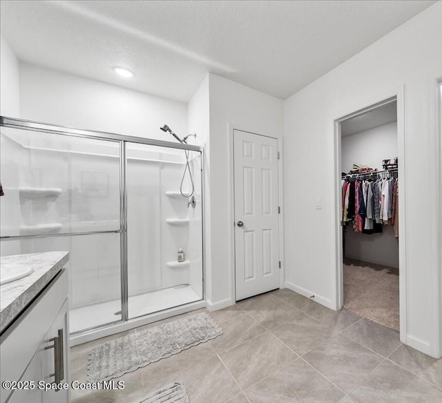 bathroom featuring vanity, tile patterned floors, a textured ceiling, and a shower with shower door