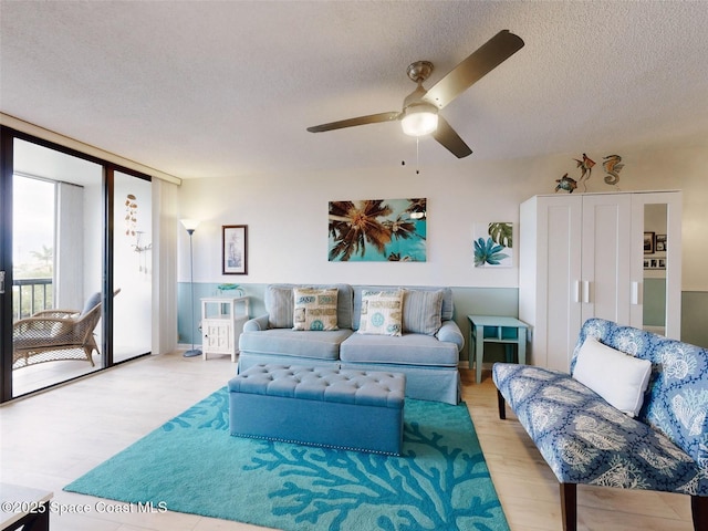 living room featuring ceiling fan and a textured ceiling