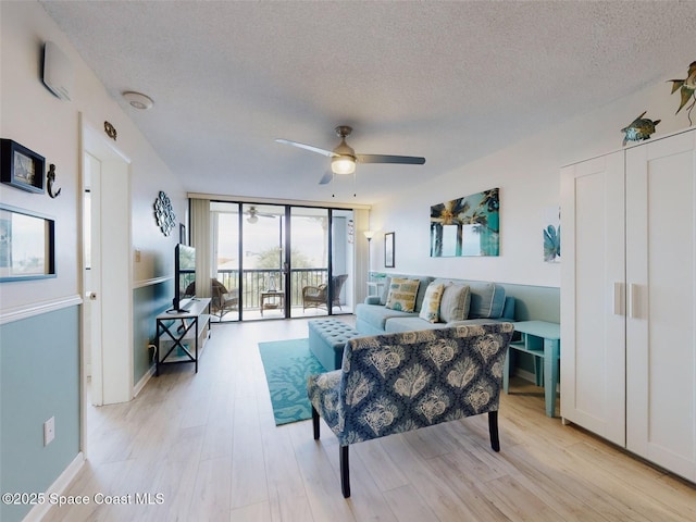 living room with expansive windows, ceiling fan, a textured ceiling, and light hardwood / wood-style flooring