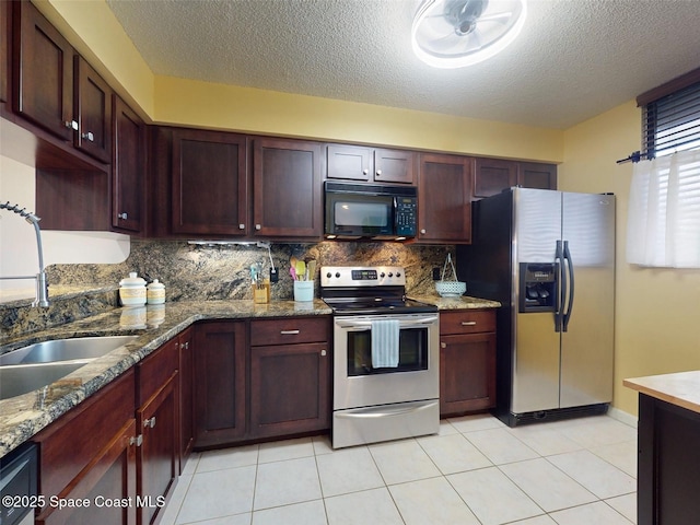 kitchen with sink, a textured ceiling, light tile patterned floors, appliances with stainless steel finishes, and stone counters