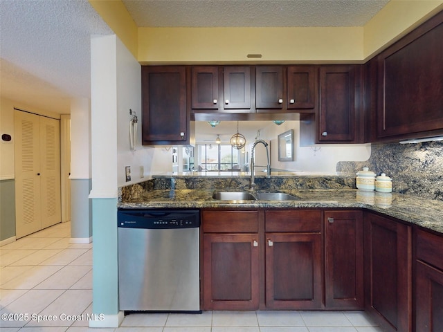 kitchen with dark stone countertops, sink, light tile patterned floors, and dishwasher