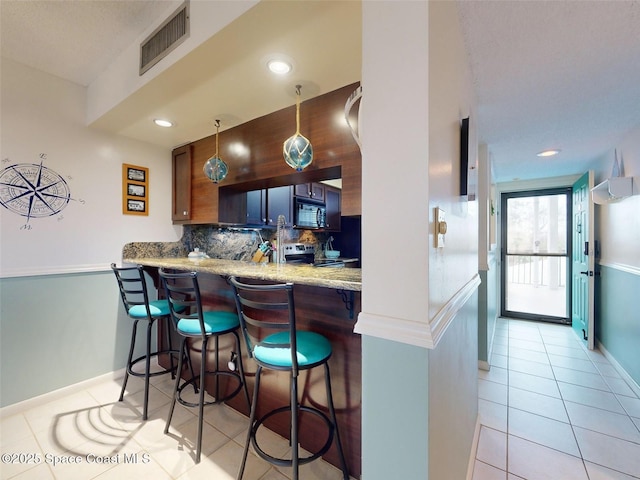 kitchen featuring light tile patterned flooring, backsplash, a kitchen breakfast bar, and kitchen peninsula