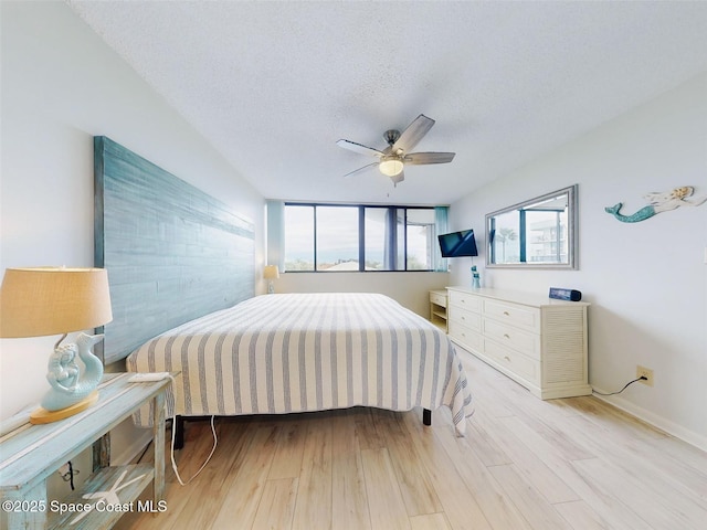 bedroom featuring ceiling fan, light hardwood / wood-style flooring, and a textured ceiling