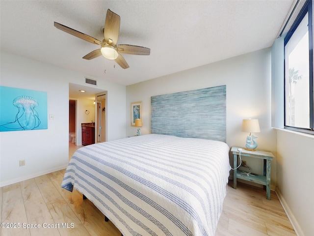 bedroom featuring ceiling fan, ensuite bathroom, and light hardwood / wood-style flooring