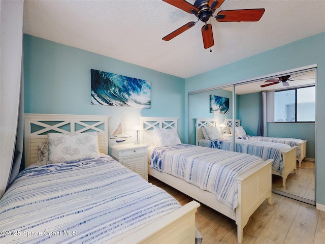 bedroom featuring a textured ceiling, light hardwood / wood-style floors, a closet, and ceiling fan