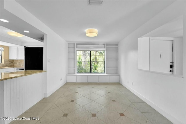 empty room with light tile patterned flooring, plenty of natural light, and built in features