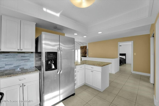 kitchen featuring white cabinets, backsplash, light tile patterned floors, kitchen peninsula, and stainless steel refrigerator with ice dispenser