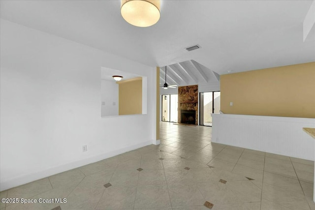 tiled empty room with a fireplace, ceiling fan, and vaulted ceiling