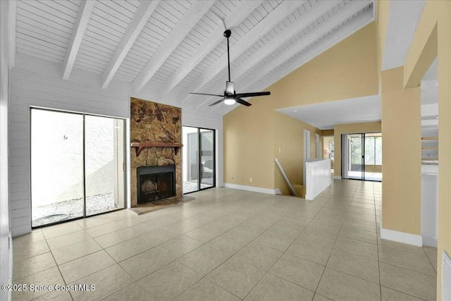 unfurnished living room with light tile patterned flooring, a stone fireplace, high vaulted ceiling, beamed ceiling, and ceiling fan