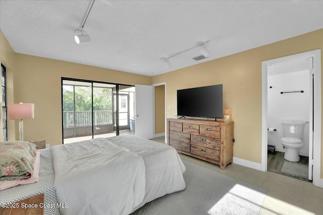 bedroom featuring access to exterior, rail lighting, a textured ceiling, and ensuite bathroom