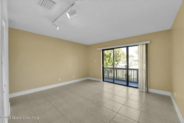 spare room featuring light tile patterned floors, rail lighting, and a textured ceiling