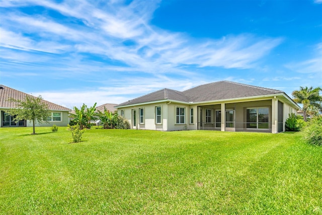 rear view of house featuring a sunroom and a lawn