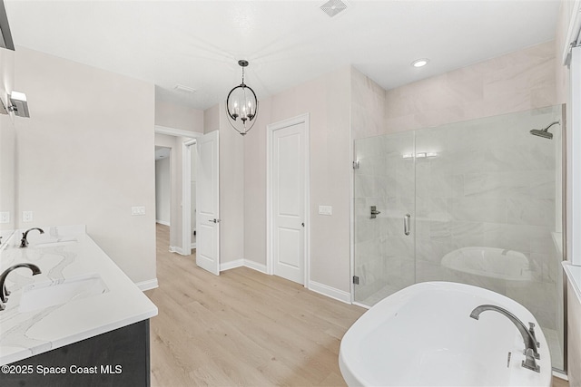 bathroom featuring vanity, hardwood / wood-style floors, a chandelier, and plus walk in shower