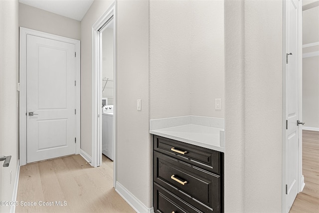 corridor with washer / dryer and light hardwood / wood-style flooring