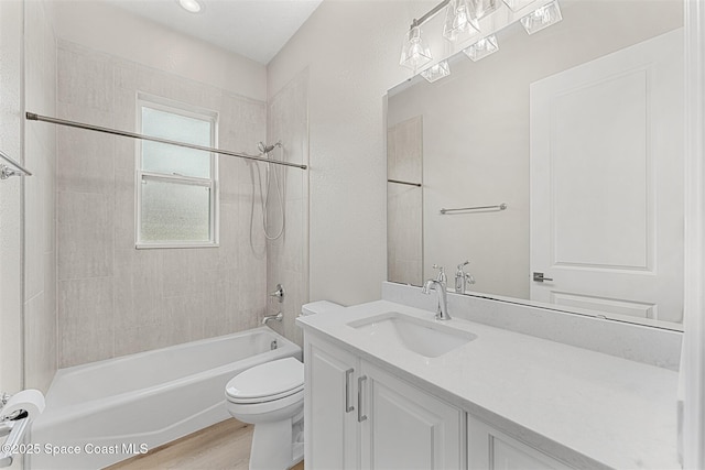 full bathroom with hardwood / wood-style flooring, tiled shower / bath, vanity, and toilet