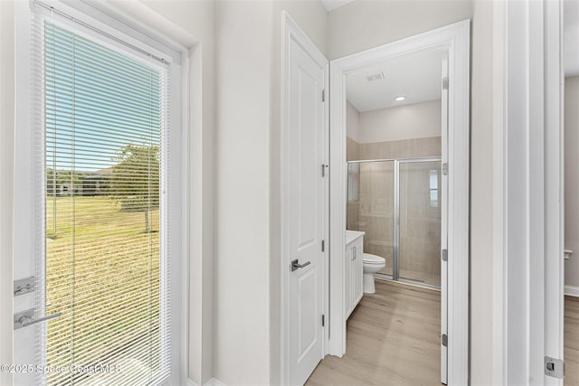 bathroom with toilet, a shower with door, and hardwood / wood-style floors