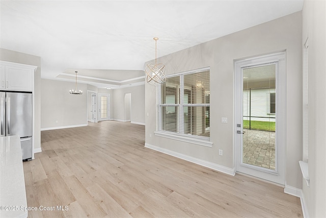 unfurnished dining area featuring a tray ceiling and light wood-type flooring