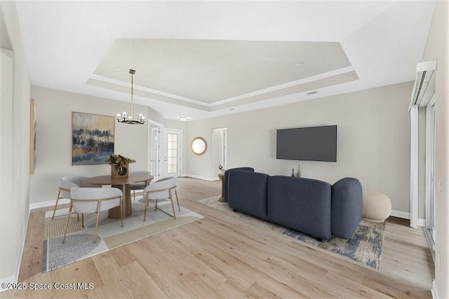 dining room featuring a chandelier, a raised ceiling, and light hardwood / wood-style flooring