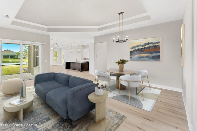 living room featuring an inviting chandelier, hardwood / wood-style floors, and a tray ceiling