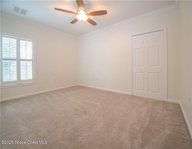 spare room featuring crown molding, light colored carpet, and ceiling fan