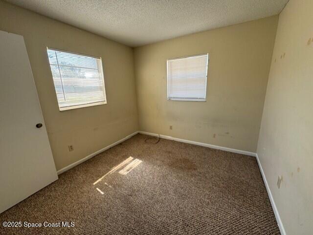 unfurnished room with a textured ceiling, baseboards, and carpet floors