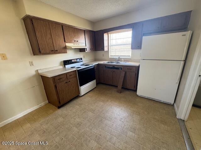 kitchen with light floors, freestanding refrigerator, a sink, under cabinet range hood, and range with electric stovetop